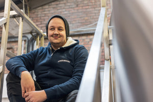 A person wearing a Gower Brewery sherpa-lined zip up hoodie in navy